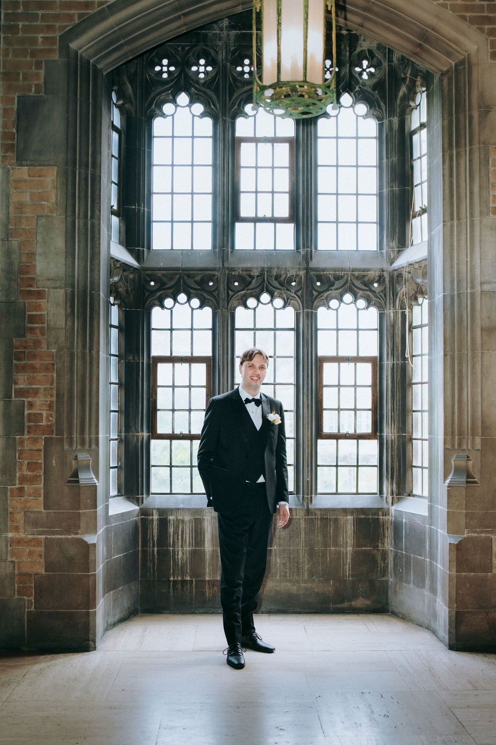 Gothic windows and exposed brick create architectural elegance in wedding venue hallway.