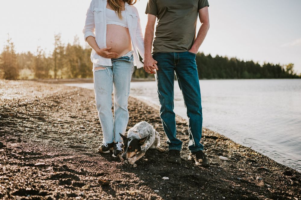 Maternity photoshoot in Comox Valley on Vancouver island couple holding pregnant belly with dog outdoor natural light photographer