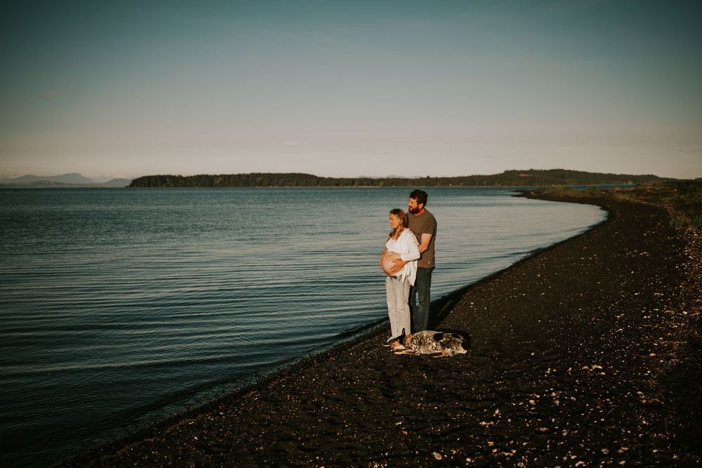 Maternity photoshoot by ocean on black sand beach Vancouver island beautiful portrait of couple by water outdoor natural light photographer