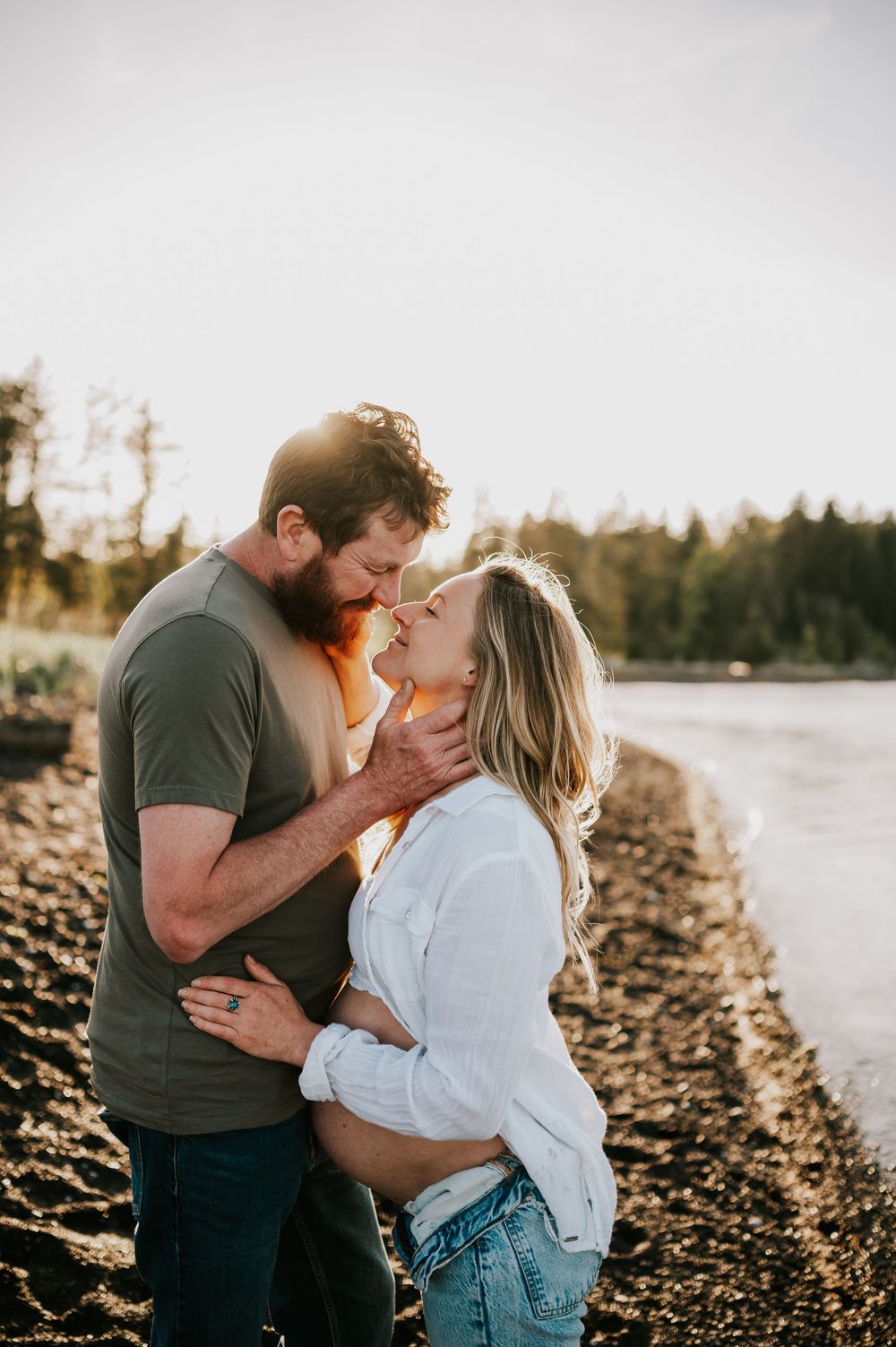 Maternity photoshoot by ocean on black sand beach Vancouver island beautiful portrait of couple kissing outdoor natural light photographer