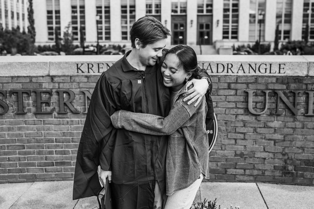 A joyful black and white moment captured between two people embracing on a college campus at Krenek Quadrangle.