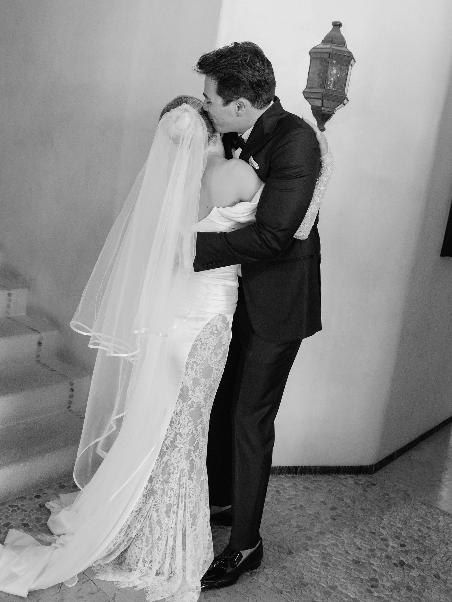 Classic black and white wedding portrait showing intimate moment on traditional staircase.