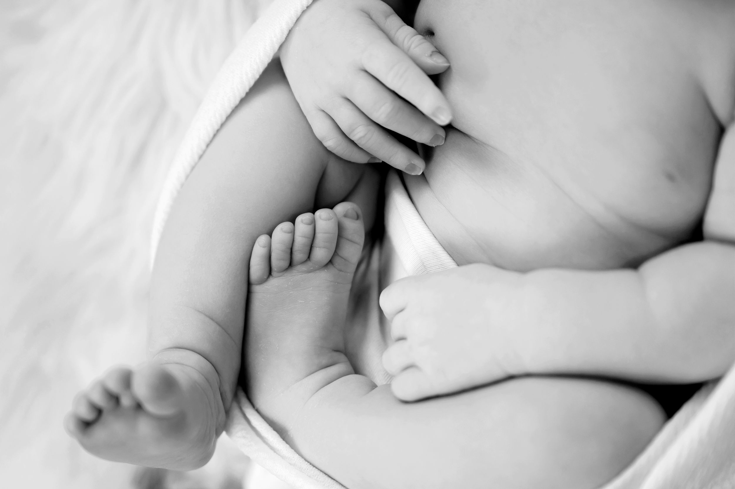 Peaceful sleeping newborn baby wrapped in soft gray blanket lying on white background during professional photoshoot.