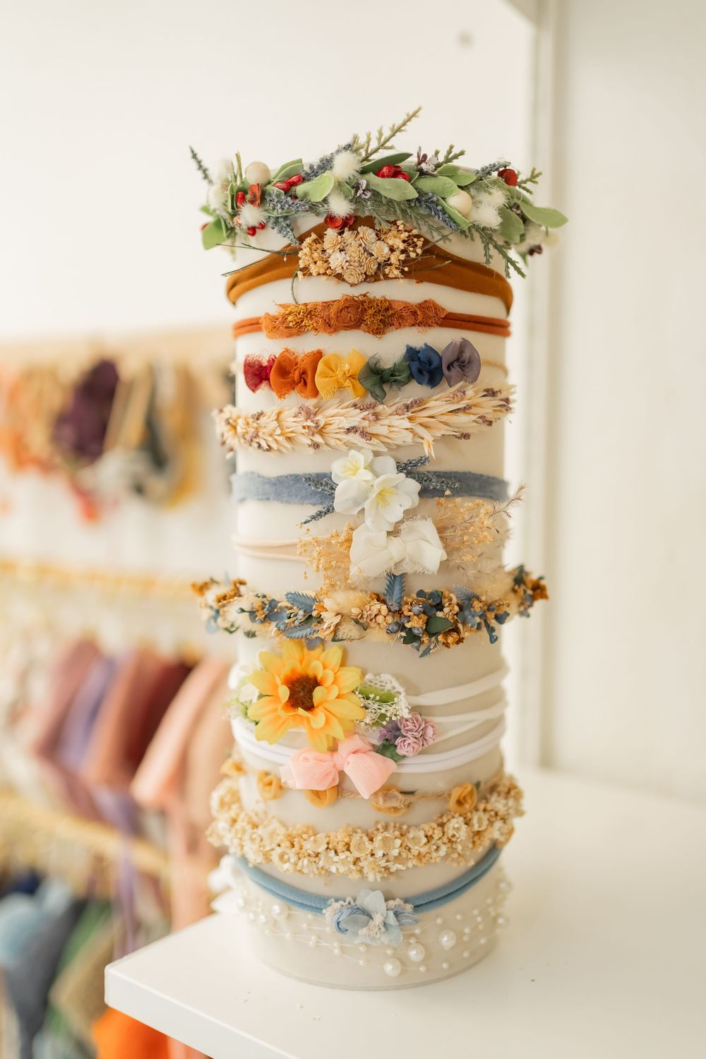 Beautiful wedding cake decorated with delicate floral arrangements, gold accents, and pastel blue ribbons on a white table.