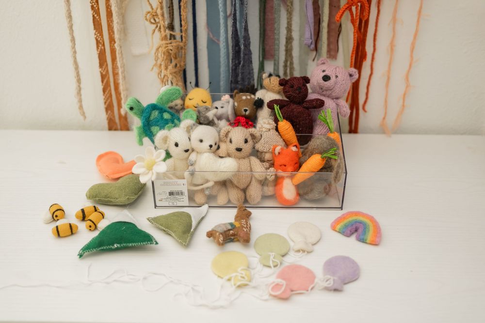A collection of small decorative objects including toys and figures arranged in a row on a white shelf.