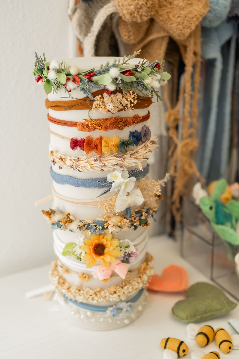 Decorative handmade stacked buttons adorned with dried flowers, ribbons and delicate embellishments in pastel colors.