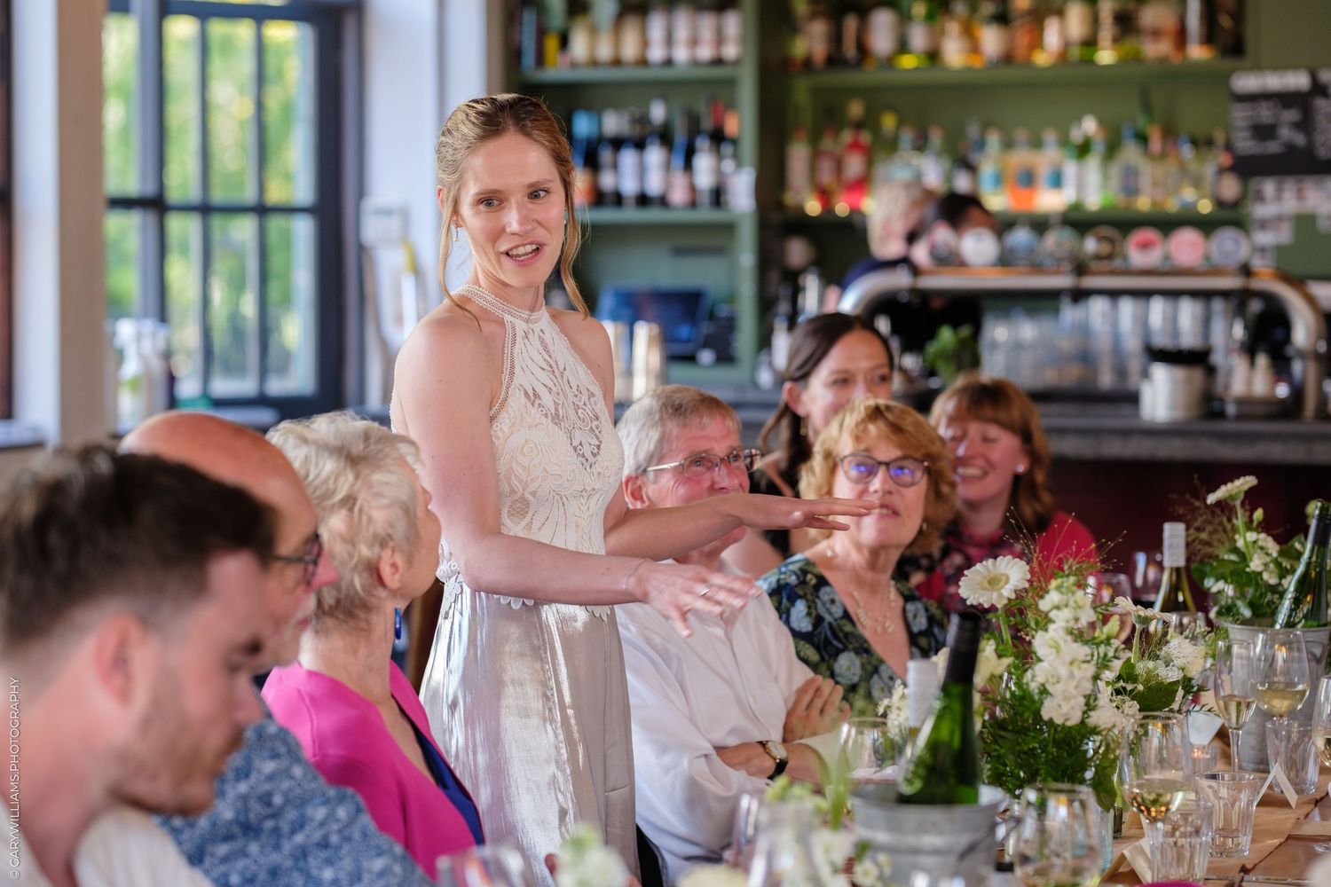 People enjoying a celebratory meal with wine glasses and floral centerpieces at an elegant dining table.