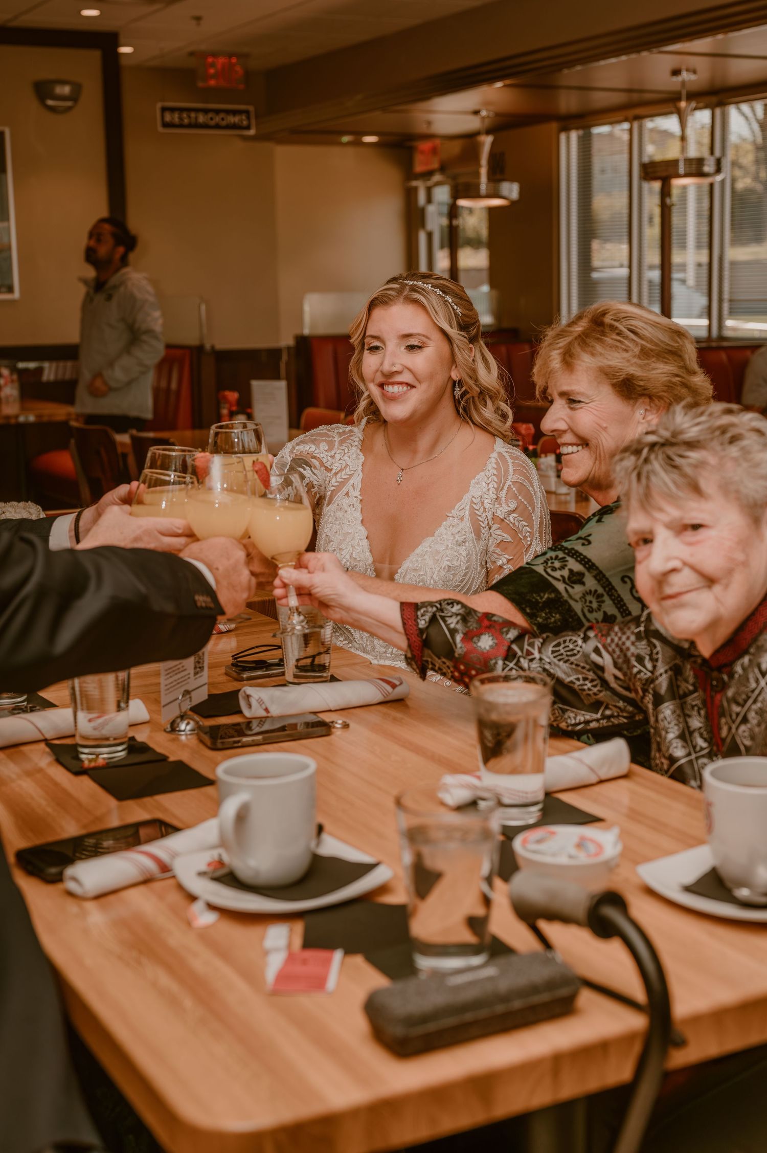 A group raises champagne glasses in a toast at a wooden table in a cozy restaurant setting.
Photo by Samantha Campbell Imagery