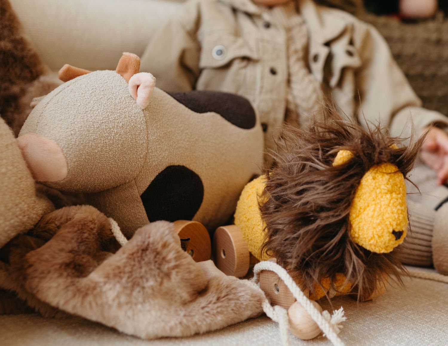 Plush stuffed animal toys including cow and lion arranged on soft surface.