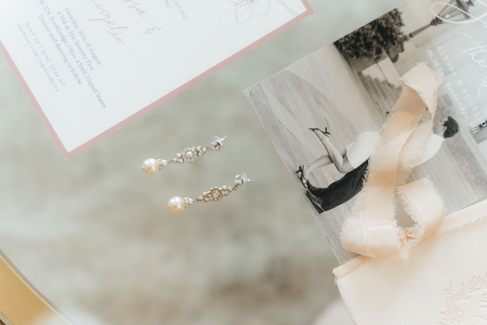 Pearl earrings and romantic vintage photos arranged on a white surface with soft blush tones.
