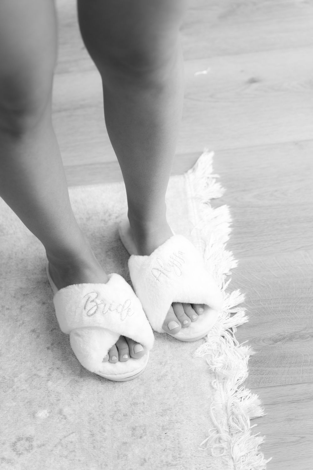 Cozy white bridal slippers with feather details shown in black and white photography.