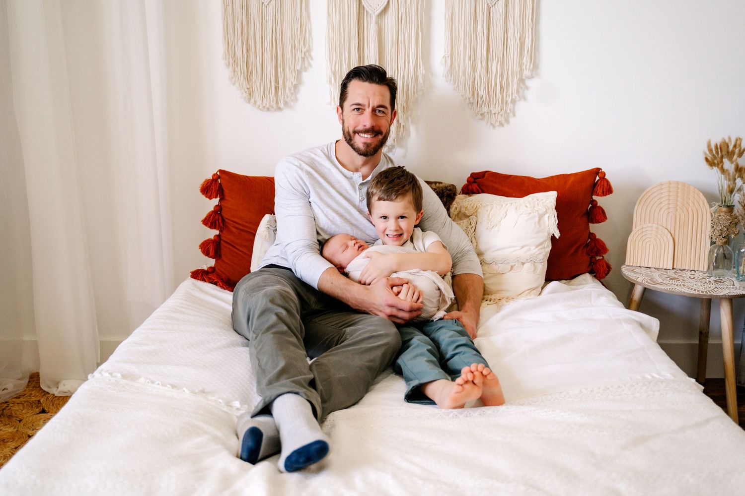 Parent and child share tender moment together while sitting on white bed with decorative pillows.