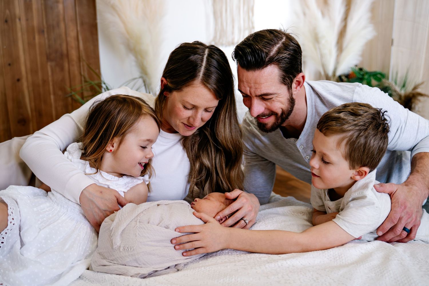 A family gathered on a bed sharing an intimate moment with their newborn.