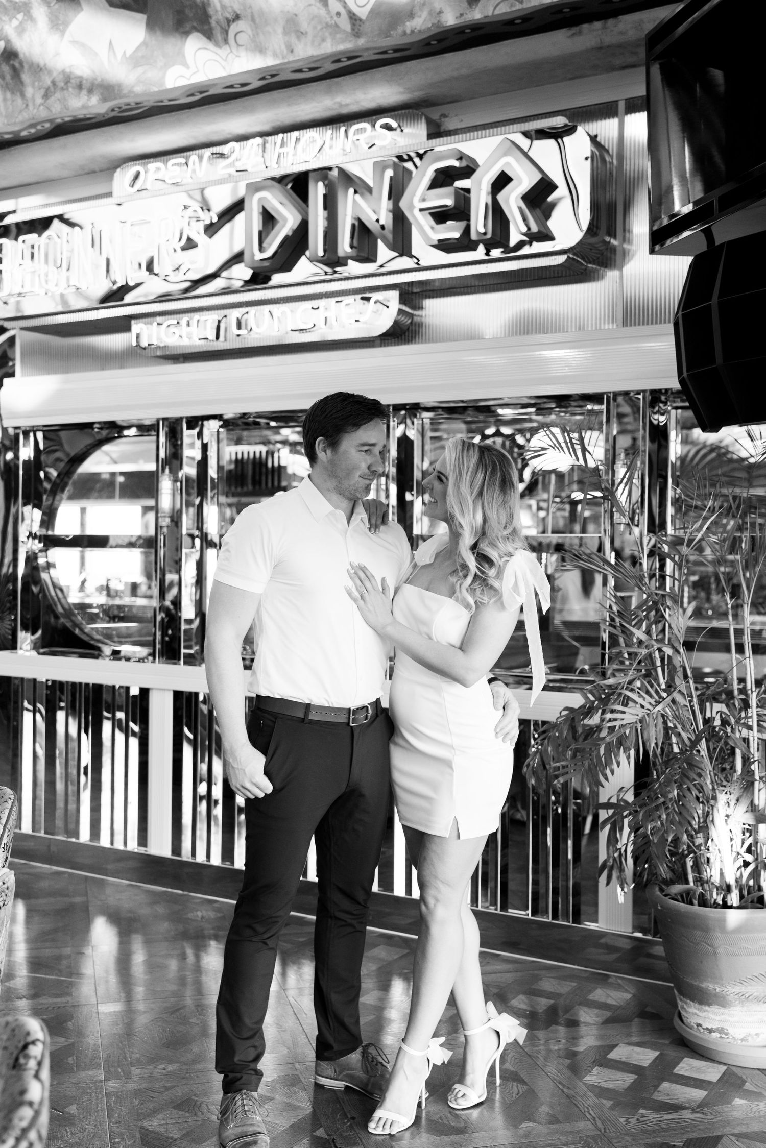 Couple in white and black outfits pose in front of retro diner signage in black and white. Jessica Paige Photo Co. Best Engagement Photos
