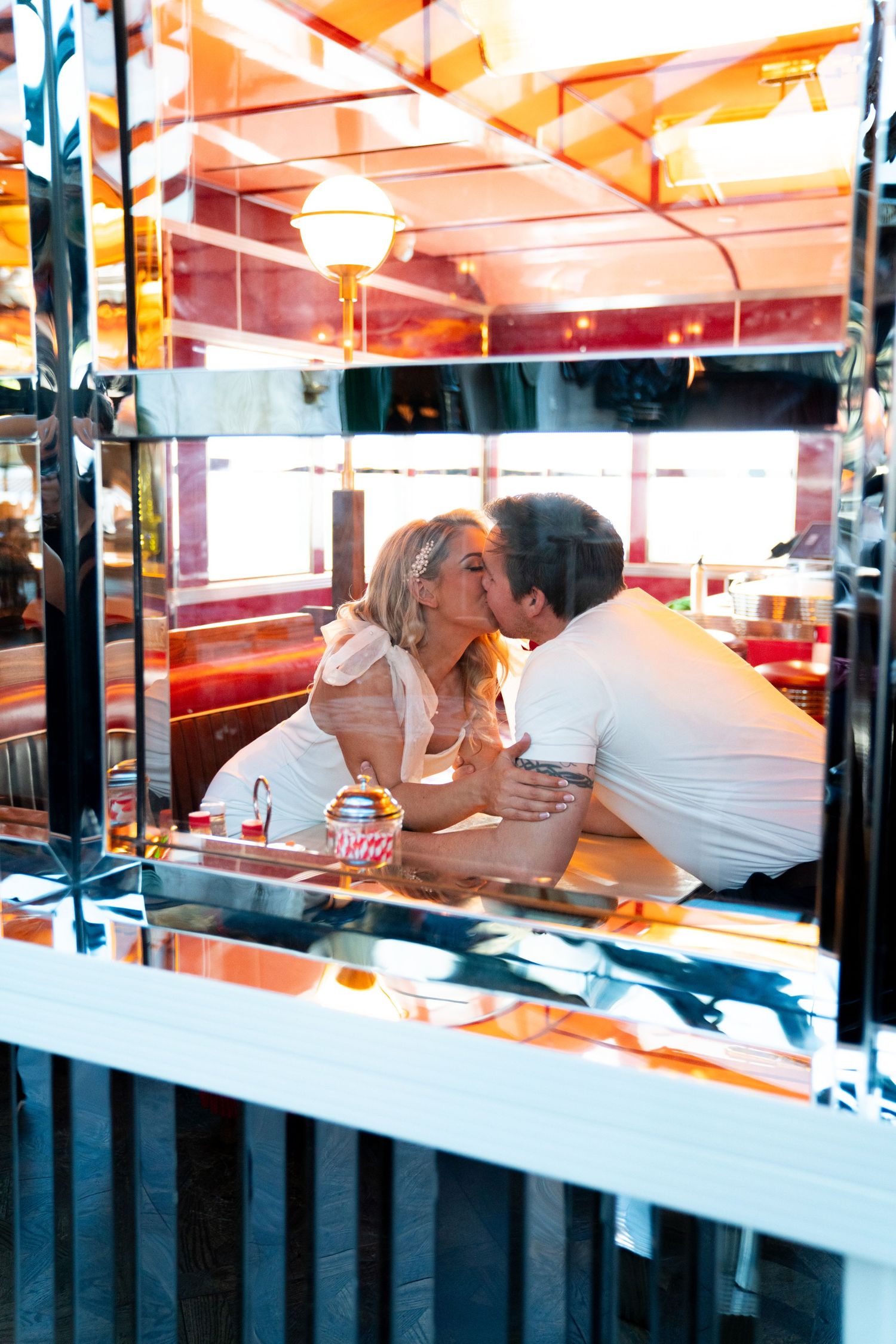 Intimate moment shared at a vintage-style diner booth with warm lighting. Jessica Paige Photo Co. Best Wedding Photographer. Cinematic photo
