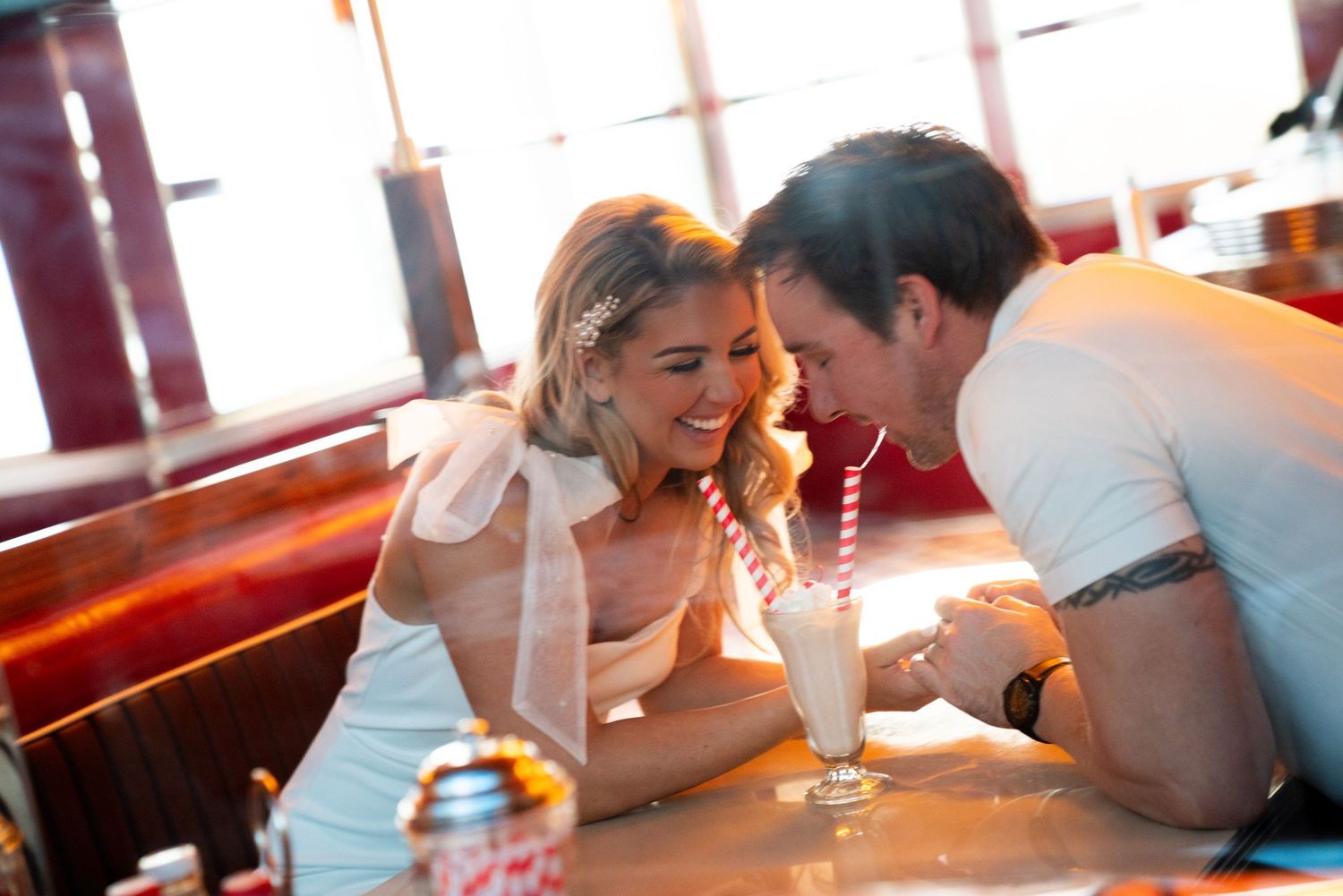 Couple sharing a milkshake at a classic American diner booth. Jessica Paige Photo Co. Best Wedding Photographer.