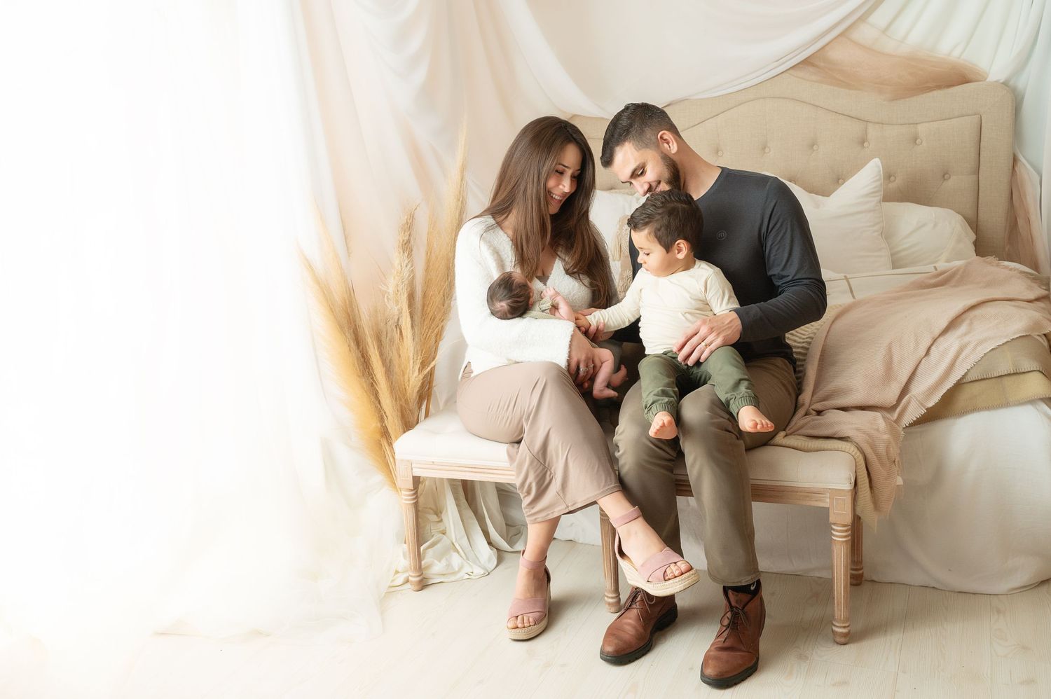 Family portrait session in studio with cream backdrops and coordinated neutral outfits.