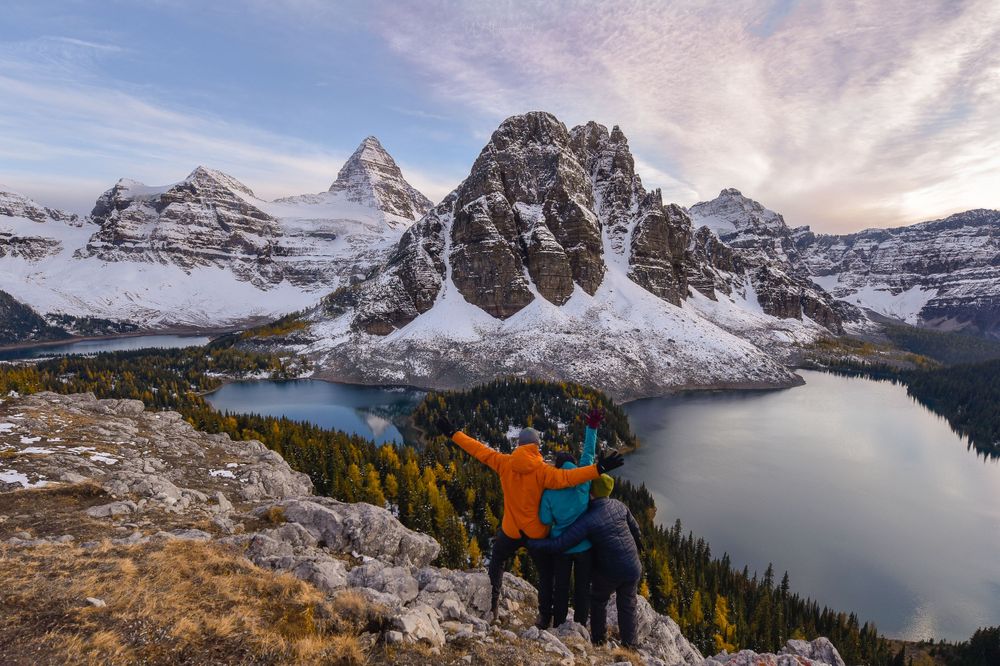 Adventurers enjoy the spectacular view of Mount Assiniboine and surrounding peaks from a rocky overlook.