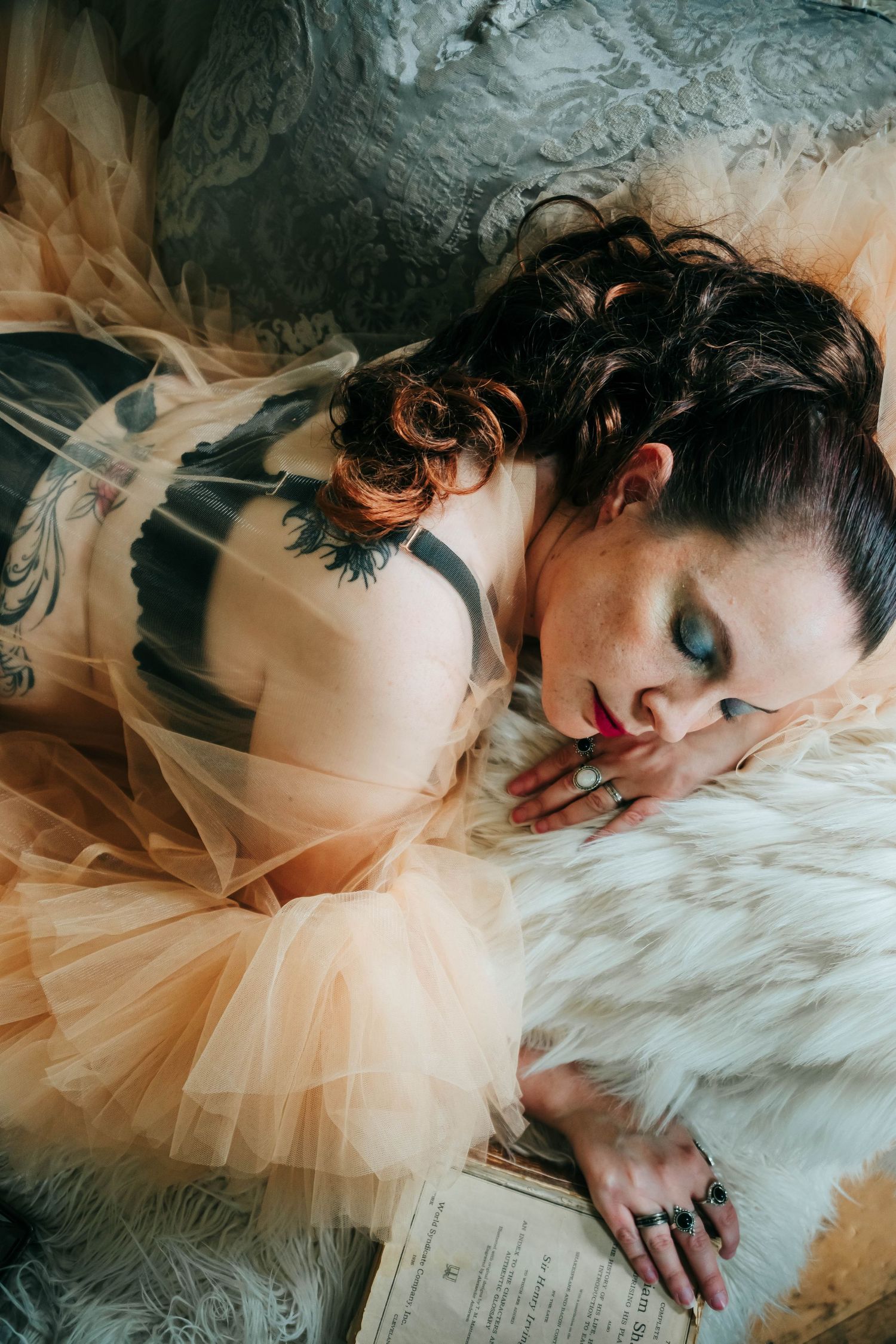 Dreamy boudoir photograph with ethereal peach tulle dress and soft white fur styling details.