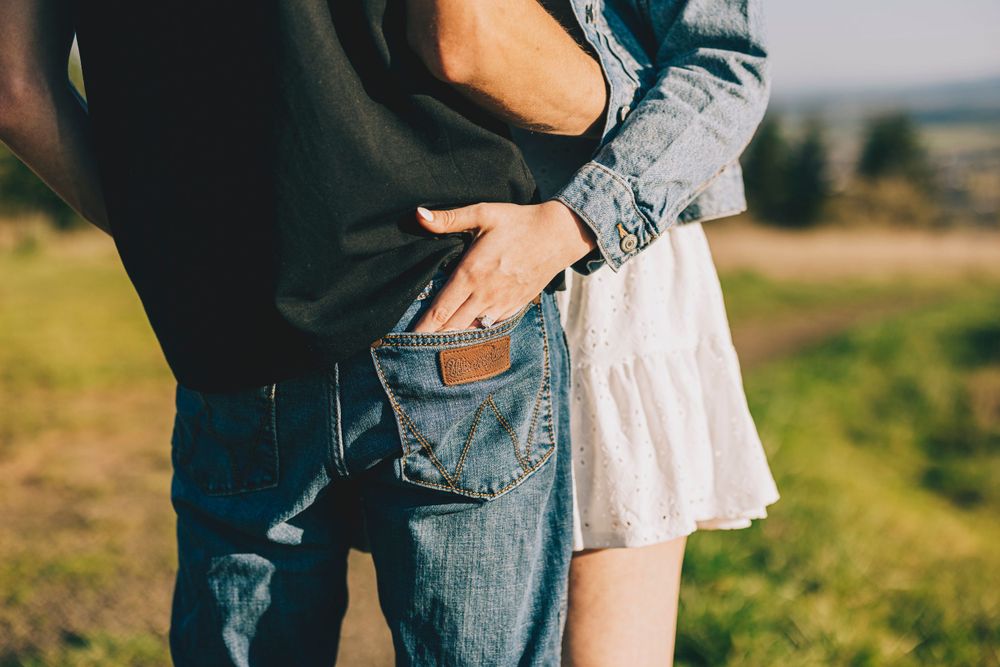 Intimate shot of a couple in casual clothing standing close together against a blurred outdoor background.