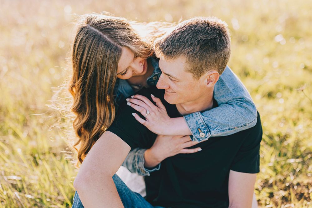A couple embraces in a golden field during sunset while sharing an intimate moment together.