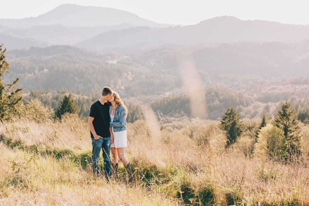 A couple sharing a quiet moment overlooking a scenic mountain valley at sunset.