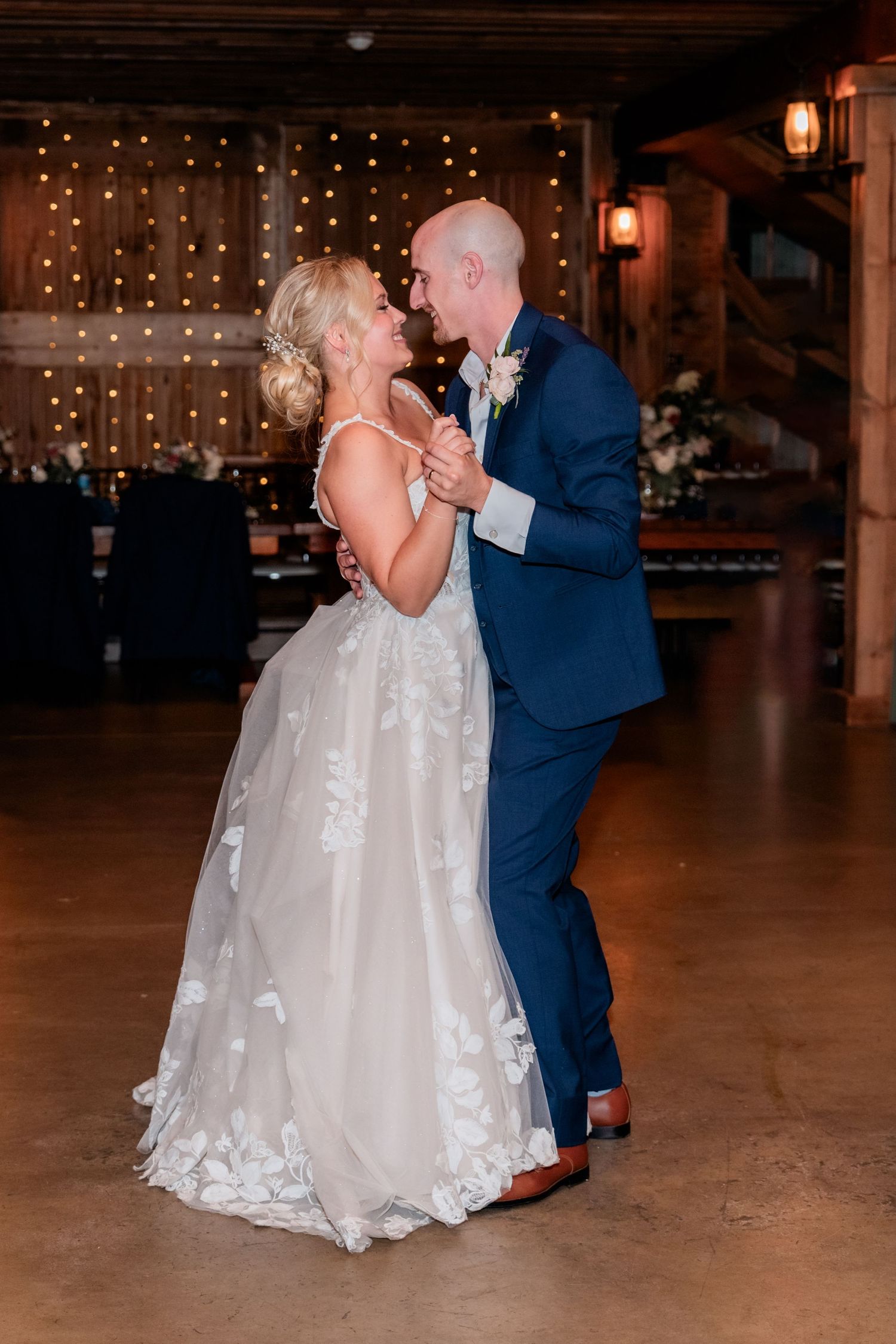 A couple shares their first dance at their wedding reception, with twinkling lights creating a romantic ambiance.