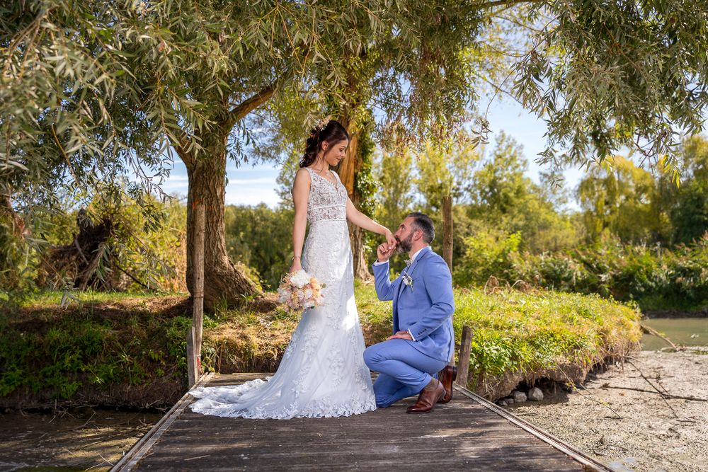 Romantic wedding portraits captured along a tree-lined path near water.