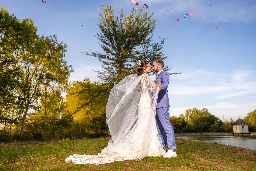 Wedding couple posing on hilltop during golden hour with rose petals floating in breeze.