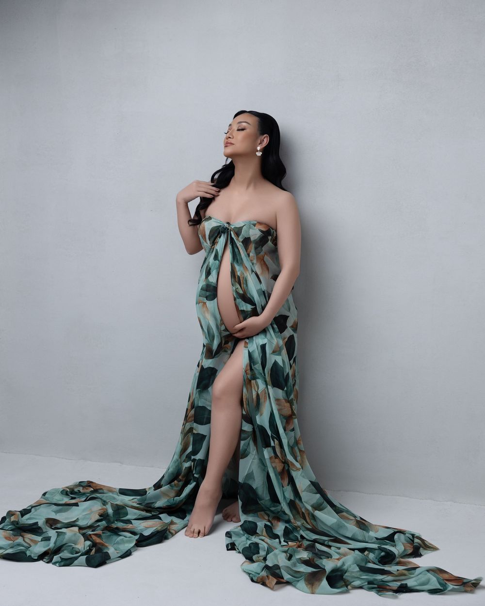 Artistic photography series showing model draped in flowing teal floral fabric against light grey background.