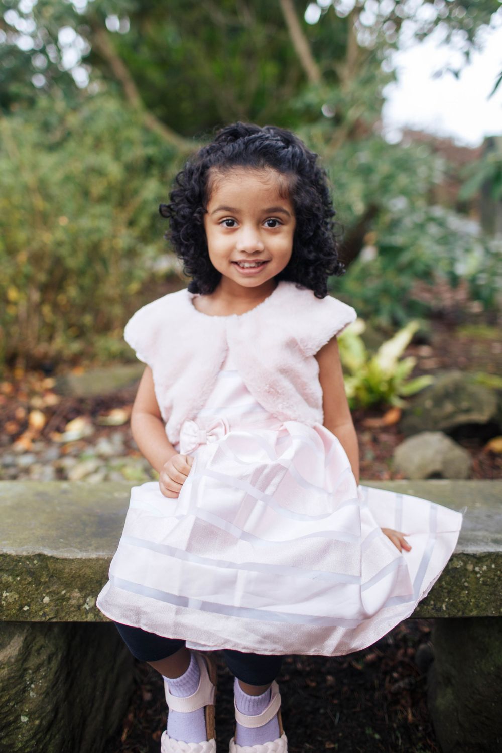 Seattle family photographer: A portrait of a young girl sitting outdoors during a photo session against a green natural backdrop