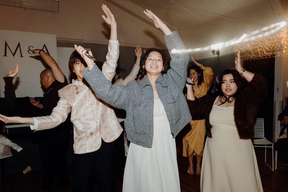 Celebration at indoor venue with guests dancing enthusiastically under string lights.