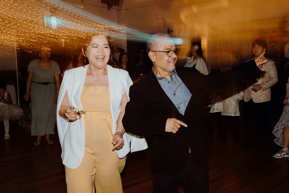 Guests dancing and celebrating at indoor wedding reception with warm lighting.