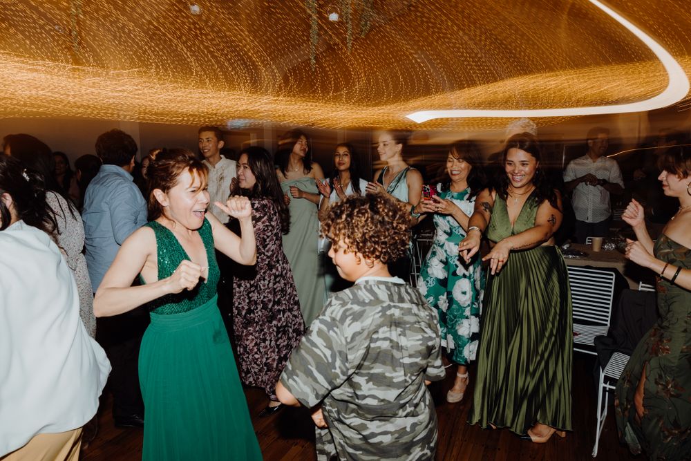 Festive crowd dancing under warm lighting at an indoor celebration.