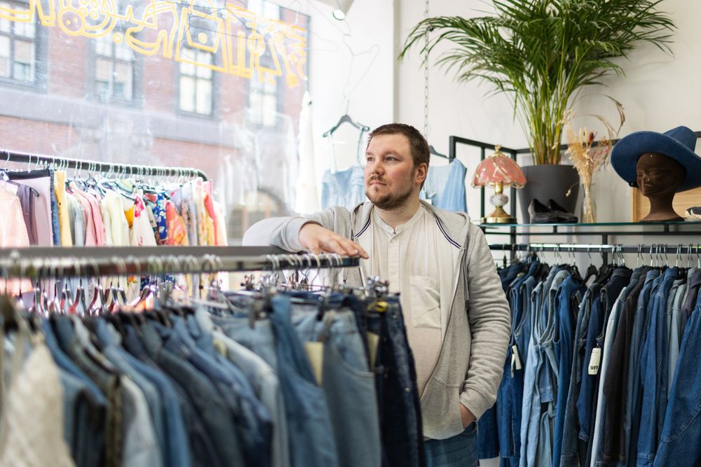 Person browsing through clothing racks in a casual retail store.