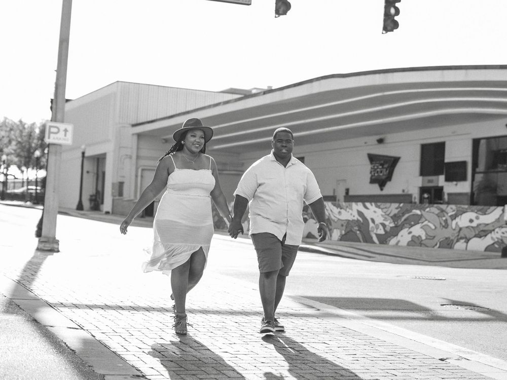 A couple walking together on a sunlit sidewalk in black and white photography.