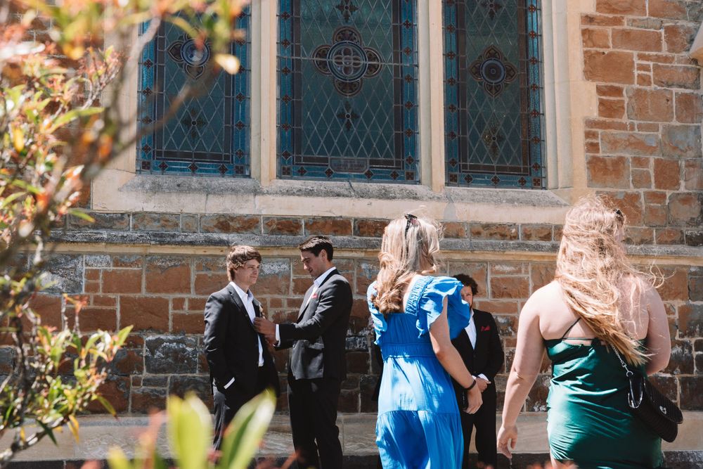 Small group gathered outside a historic brick church building with stained glass windows.