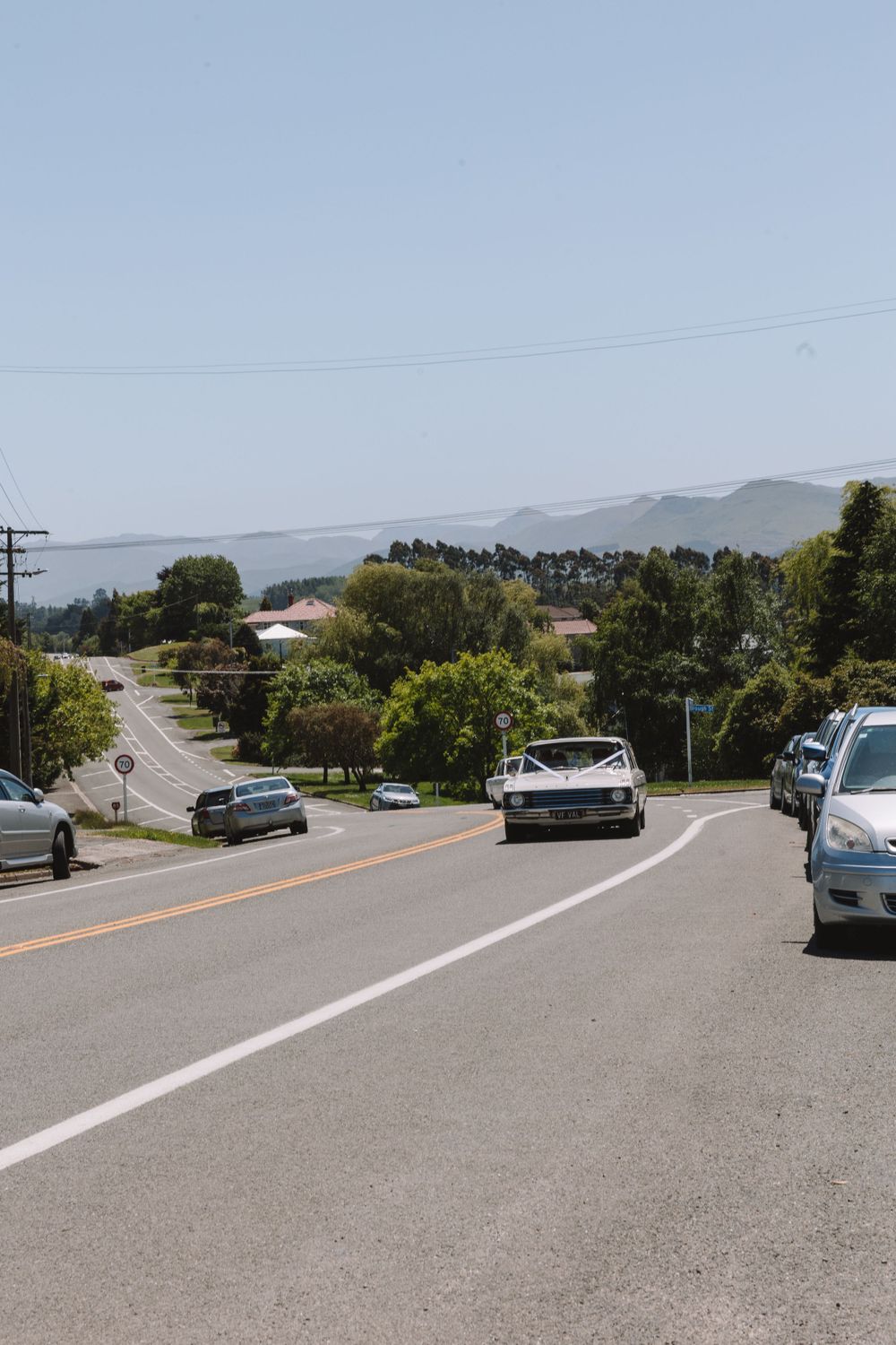 Scenic mountain road with parked cars and distant hills on a clear day.