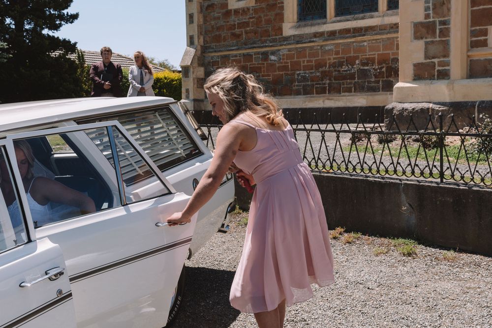 Person in pink dress preparing to enter classic white vintage car.