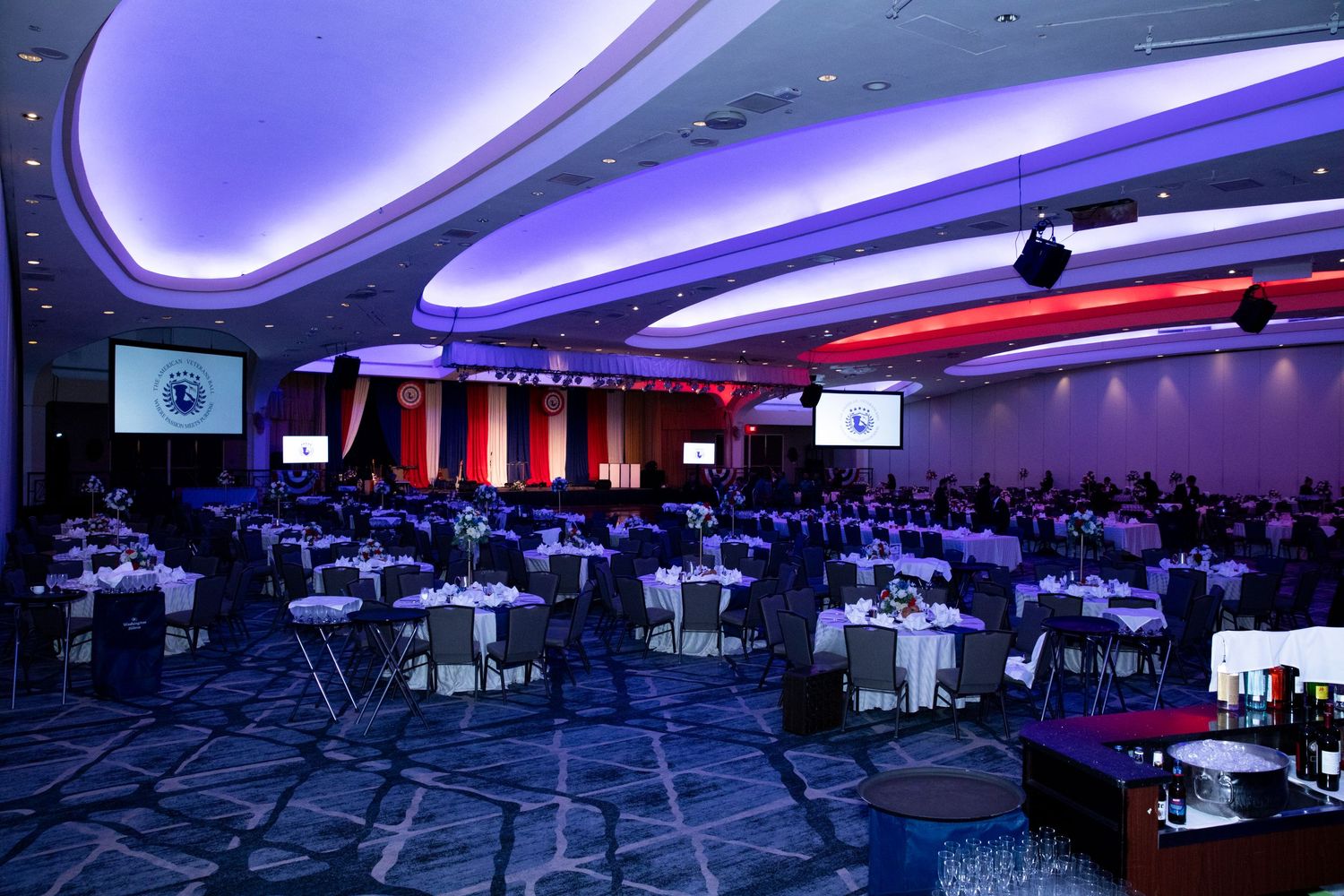 Modern event space with purple LED lighting and round dining tables.