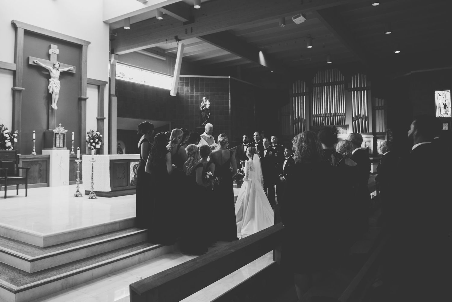 A black and white photograph showing a traditional Catholic wedding ceremony taking place inside a church sanctuary.