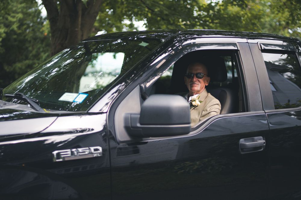 Person in wedding attire sitting in black Ford F150 pickup truck.