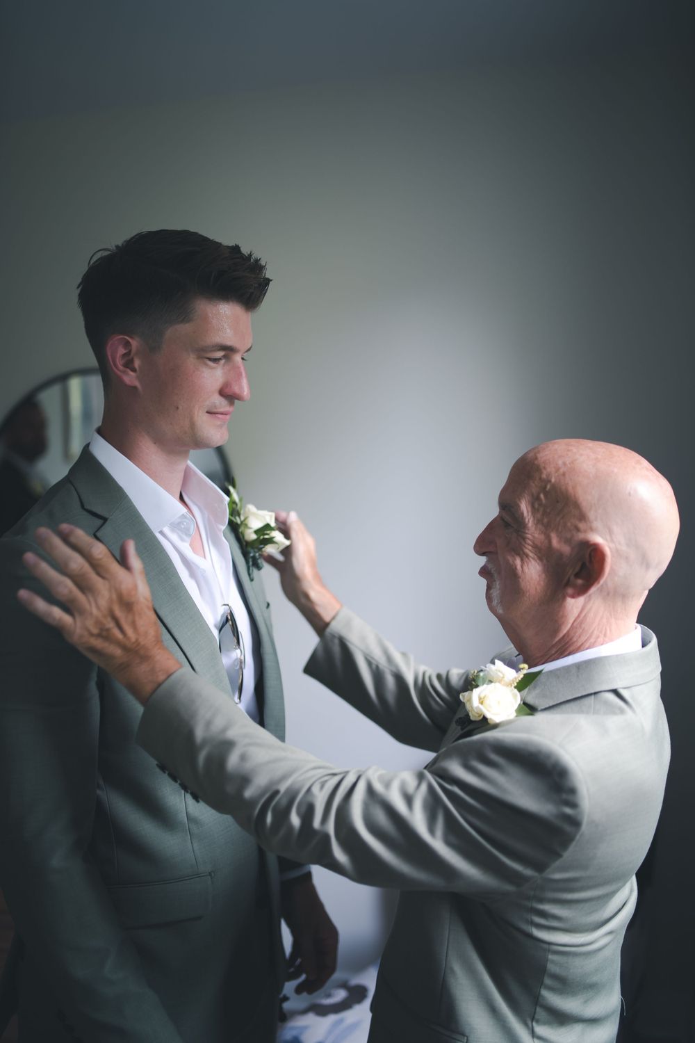 Emotional moment between two people in formal attire adjusting boutonniere.
