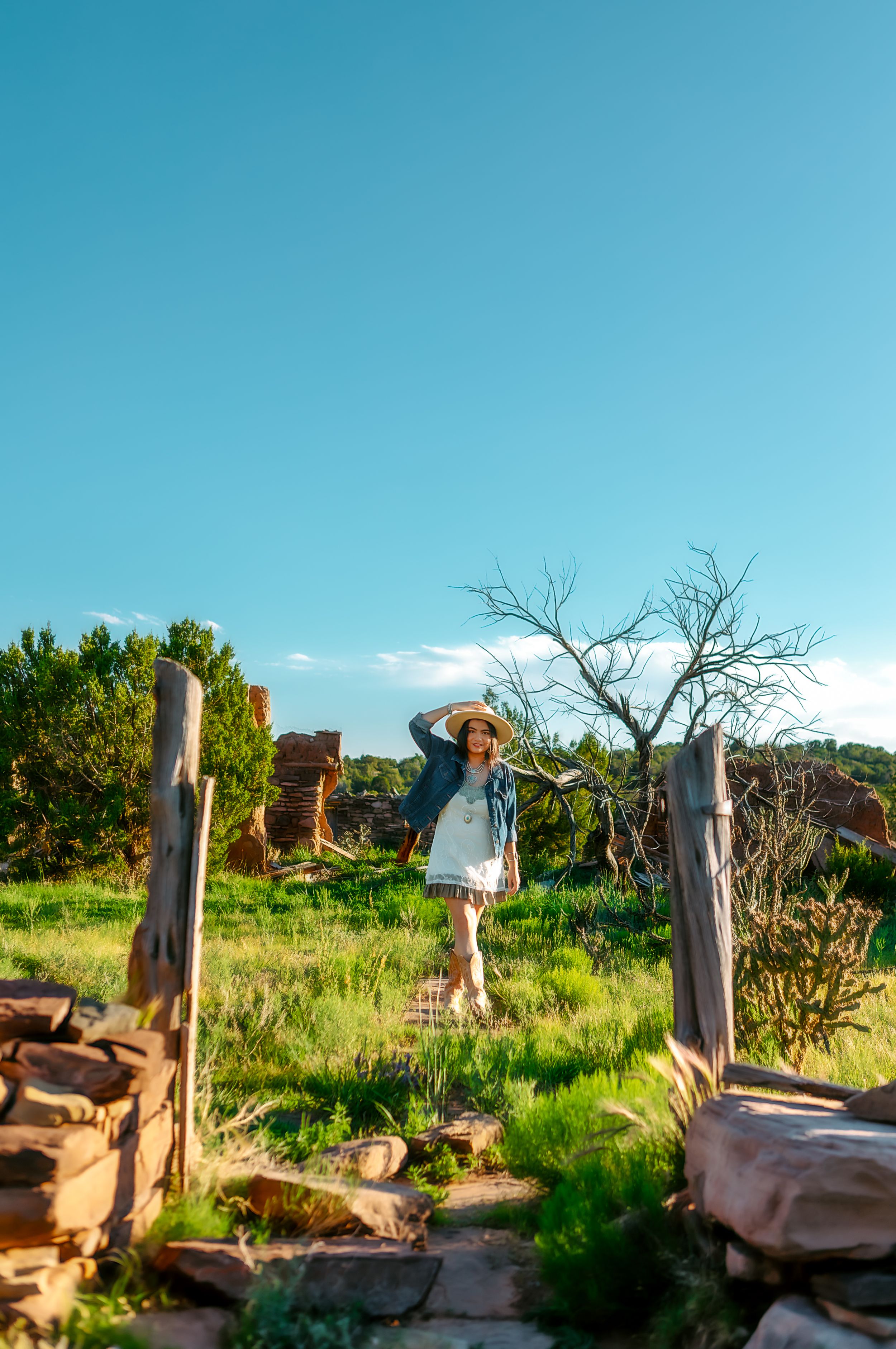 Sunny outdoor scene with wooden posts and stone walls against a bright blue sky.