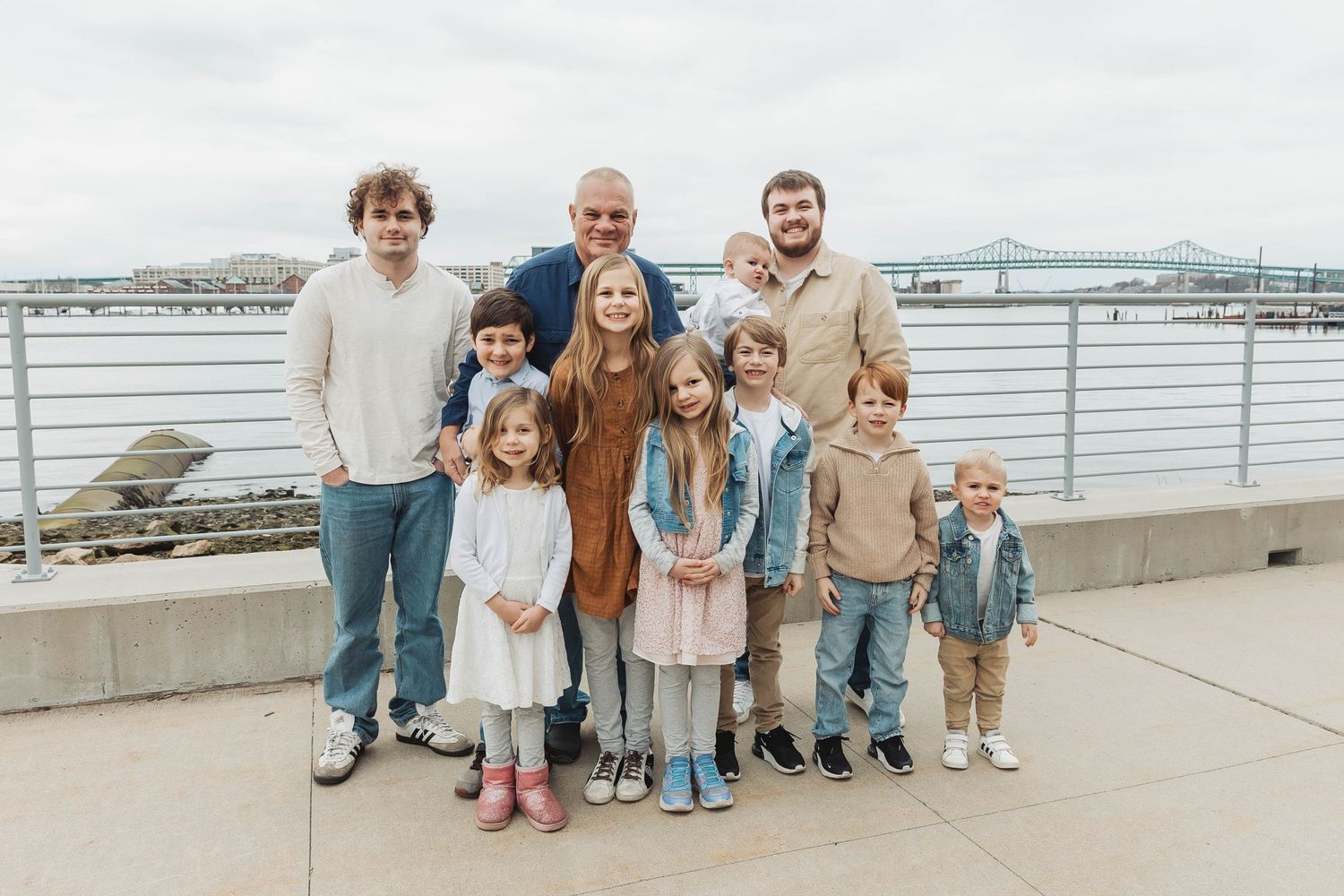 Casual family group portrait on waterfront deck with harbor views.