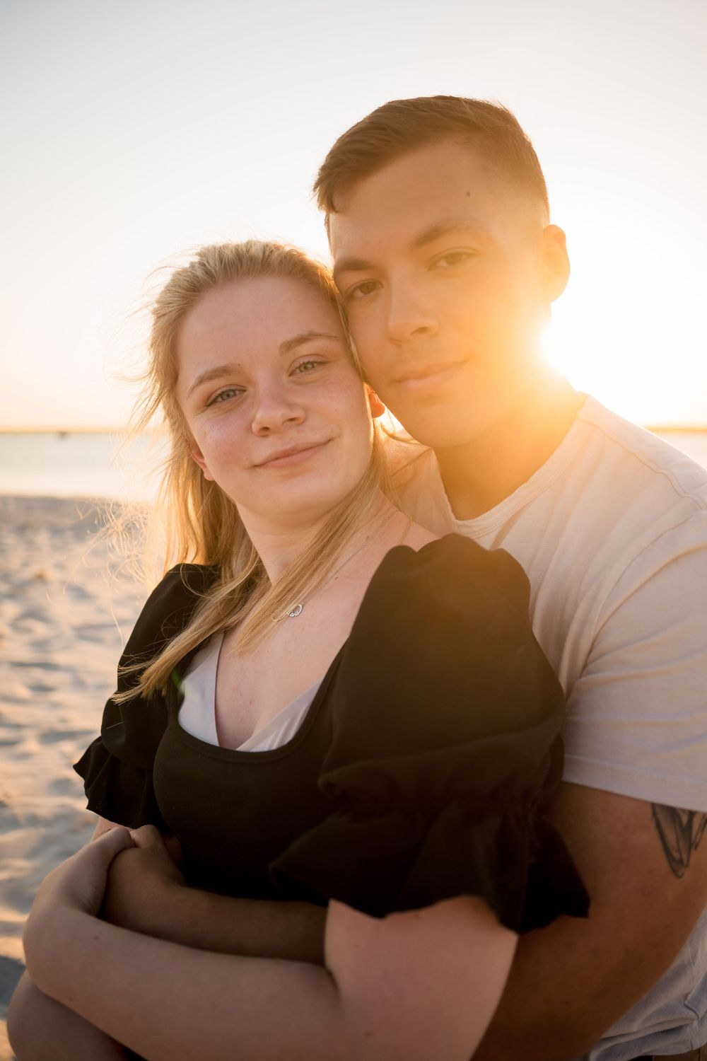 Couple sharing intimate moment on beach during golden hour sunset.