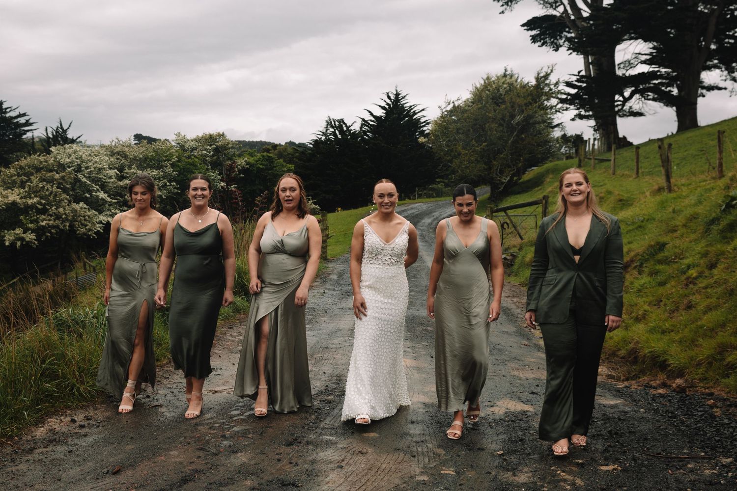 Wedding party in gray dresses walking on a misty hillside path.