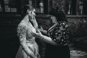 Two people share an intimate moment during wedding preparations in a vintage-style black and white photograph.