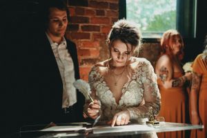 A wedding signing ceremony takes place in a rustic brick-walled venue with natural lighting.