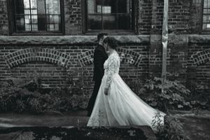Black and white photo of newlyweds against vintage brick building architecture.